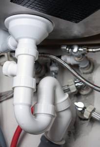 The plastic double-turn siphon consists of many parts. In the photo, the siphon is located under the dishwasher, and is equipped with an outlet for connecting a dishwasher or washing machine. 