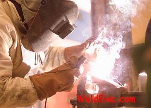 Welder welds with an electrode wearing gloves