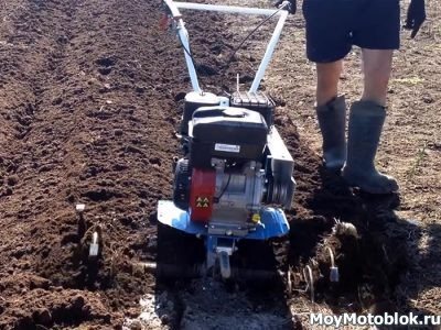 Plowing the garden with a walk-behind tractor with cutters