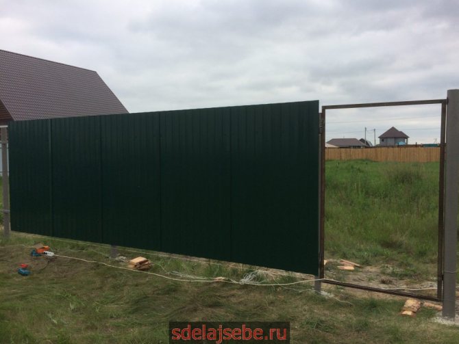 do-it-yourself fence made of corrugated sheets with metal veins from a corner